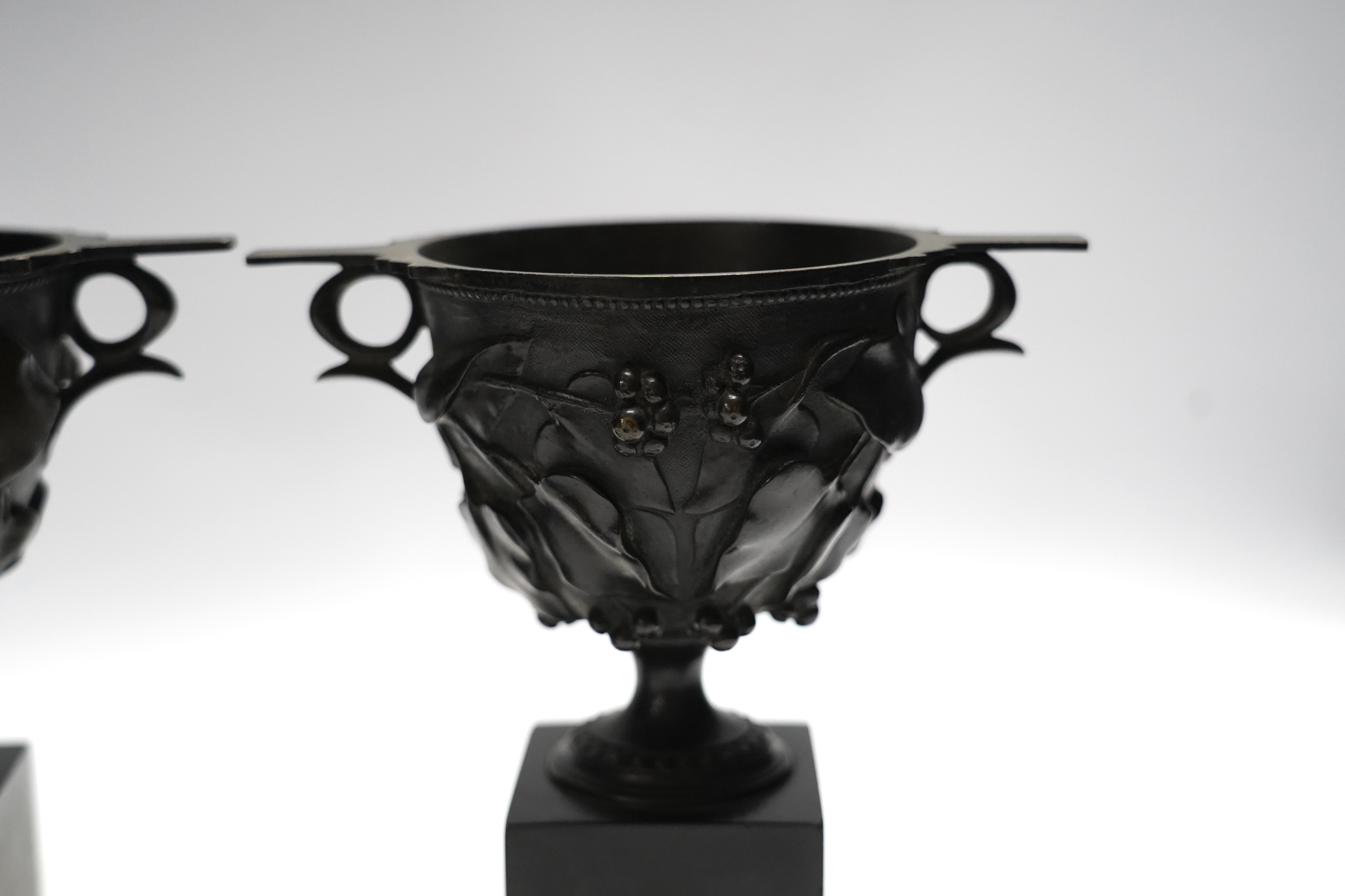 After the Antique, a pair of late 19th century bronze skyphos vessels on polished slate bases, 22cm